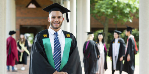 a male student wearing his graduation robe at his graduation ceremony