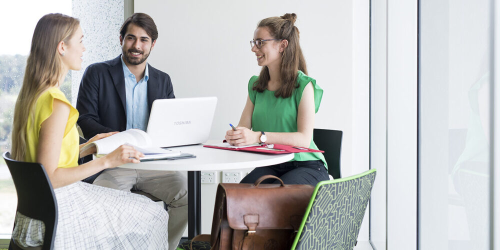 Three people in business casual wear talking around a circular table
