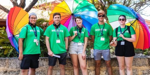 5 Curtin mentors smiling and holding rainbow umbrellas