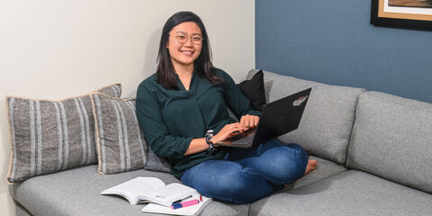 Female student sitting on a sofa holding a laptop
