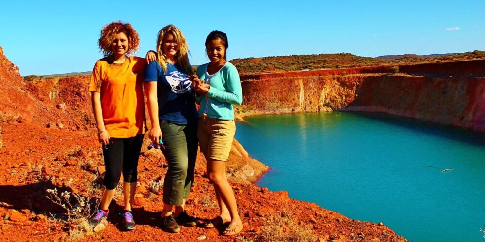Three ladies standing in front of big, blue lake