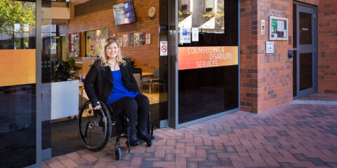 Person in wheelchair exiting Counselling and Disability Services