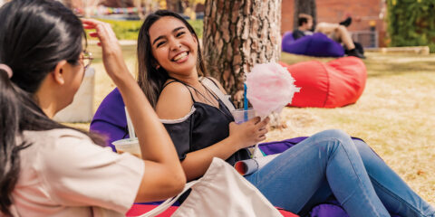 Student sits on a beanbag eating pink fairy floss