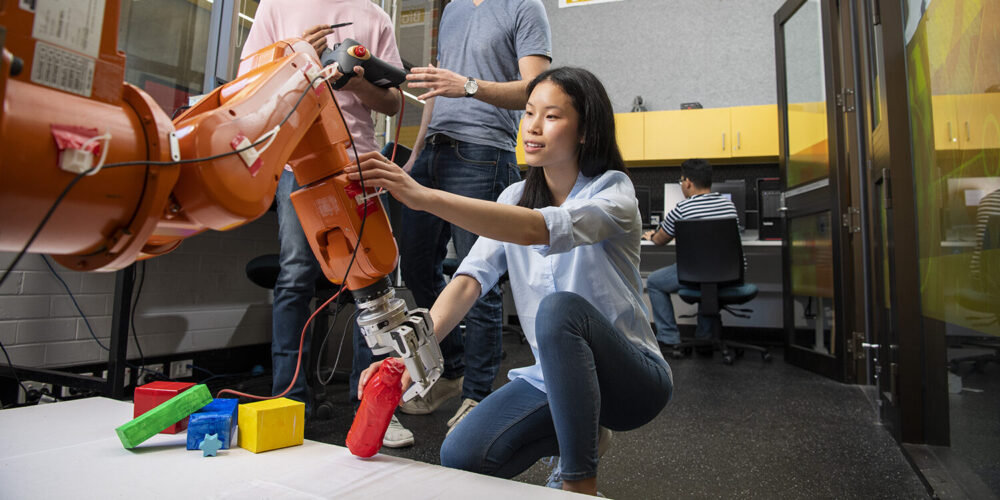 student fixing robotic arm