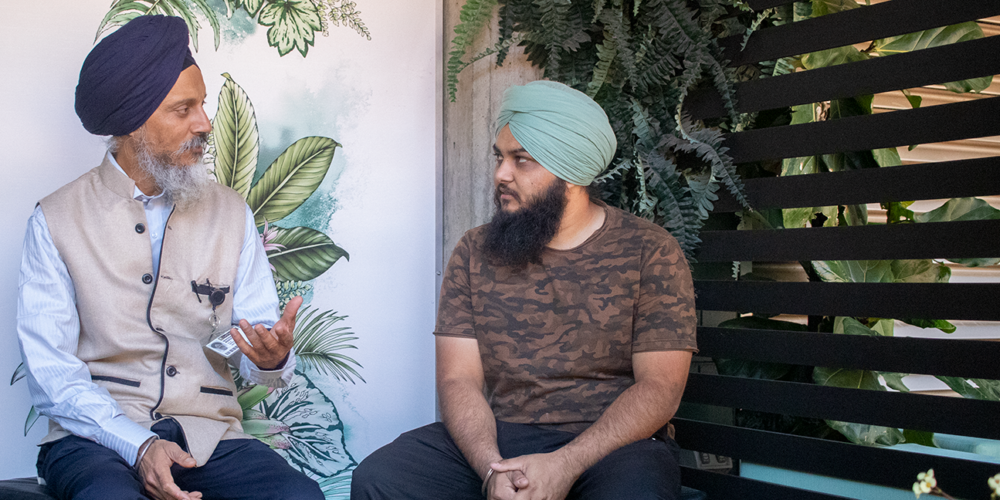 Two Sikh men talking to each other in a semi-undercover area
