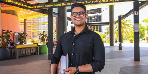 Student wearing a black shirt holding books at Wesfarmers Court