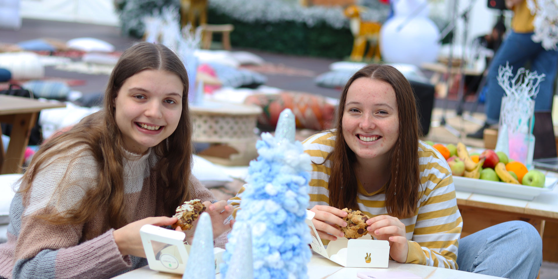 Two students sitting at a table filled with winter decorations. They smile at the camera.