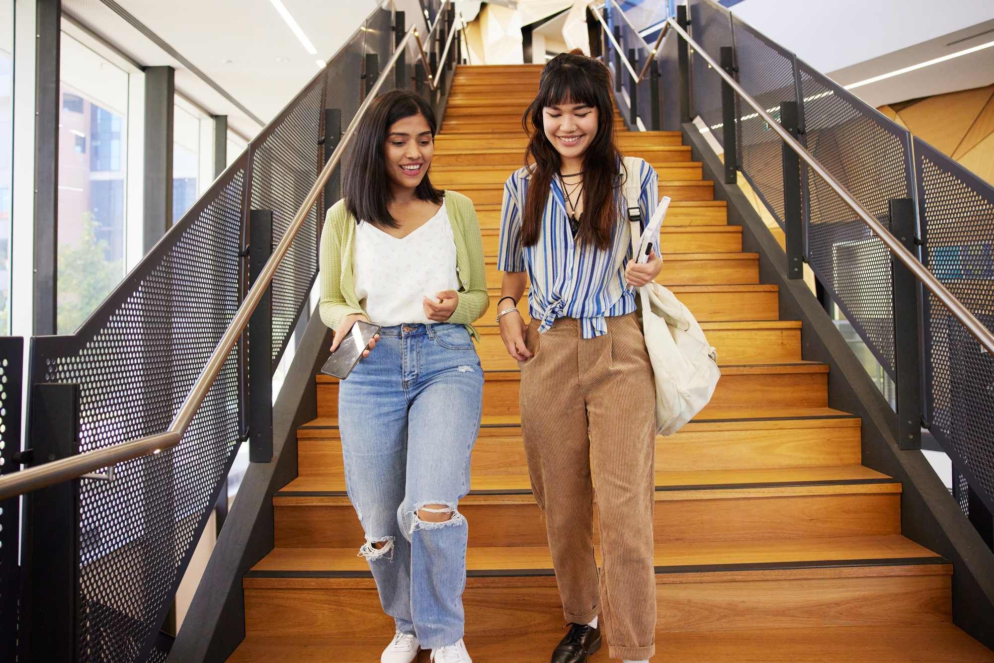 Two female students walking down stairs
