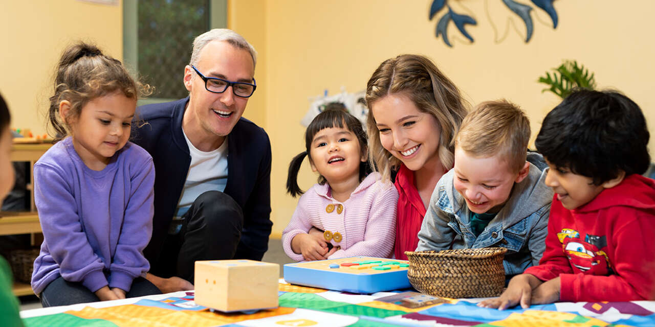 A woman and a man smiling at a table surrounded by four young children.