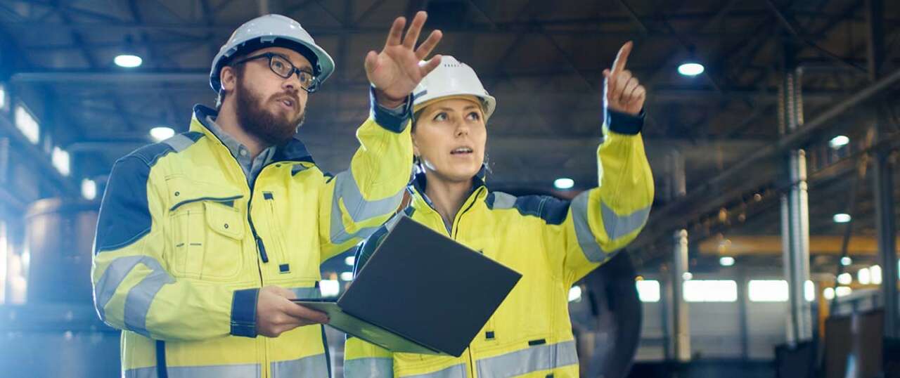 Two people in high vis jackets on a worksite