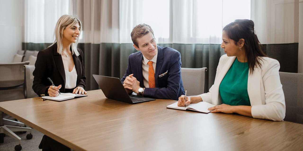 A group of four professionals looking at a shared laptop screen.