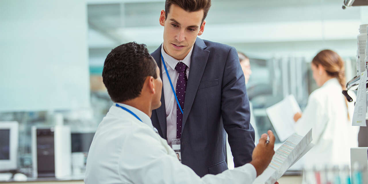 Man in a business suit talking with a scientist