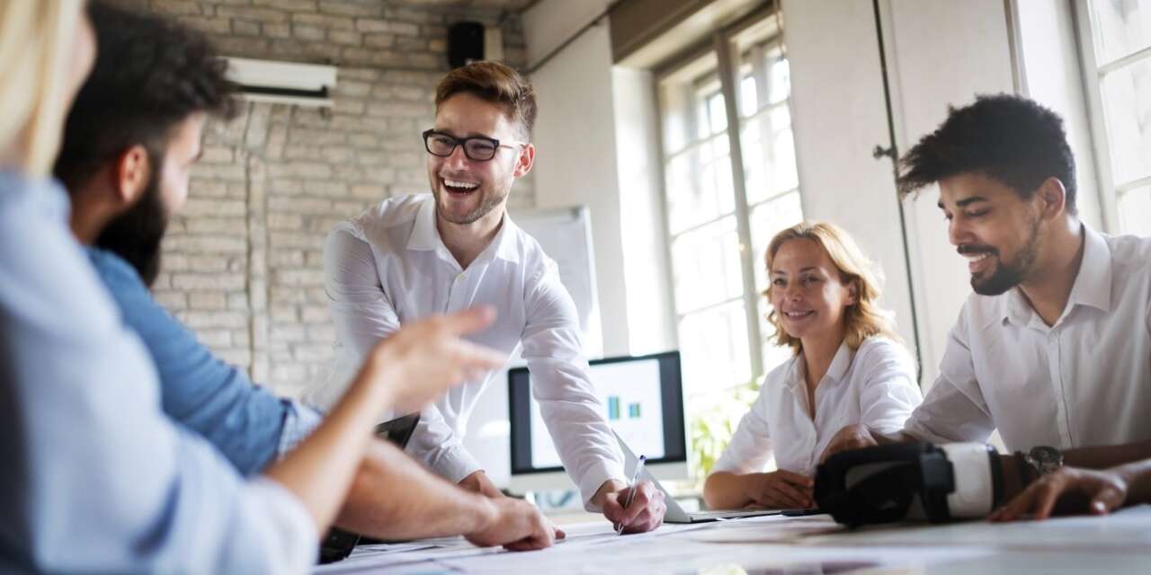 A student in her twenties talks to two younger people in a professional setting.