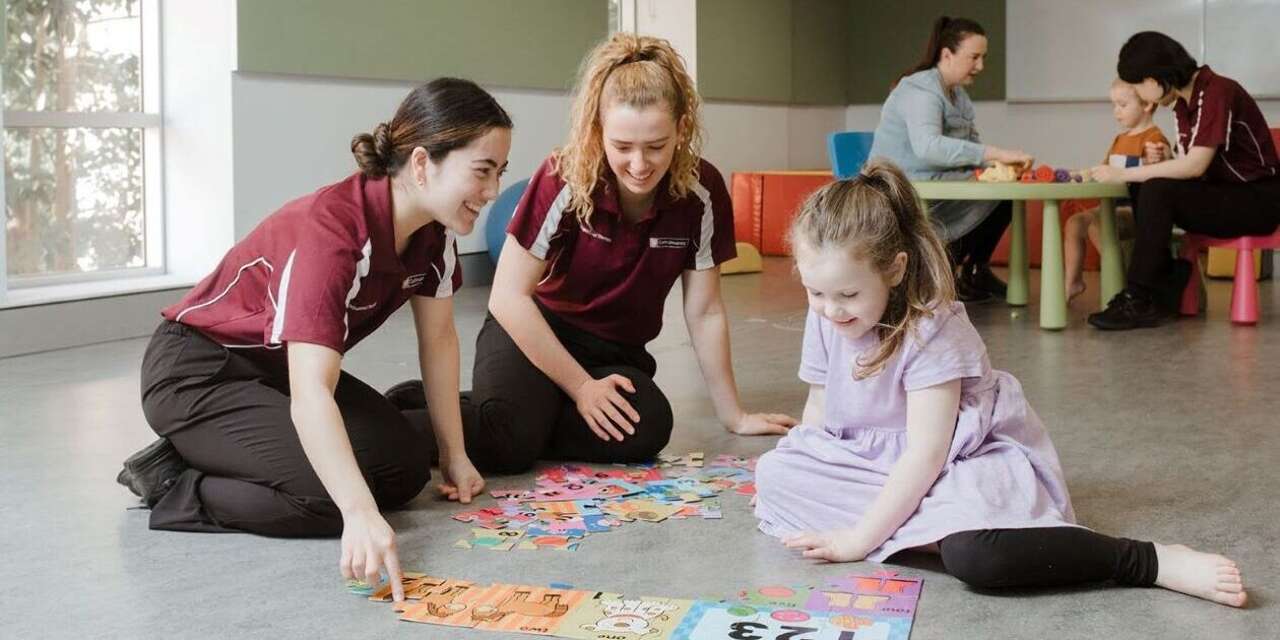 Occupational Therapy students with child and a alphabet mat
