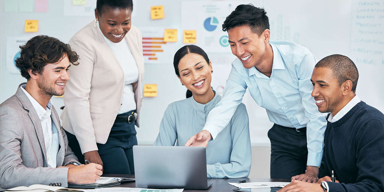 Group of colleagues smiling looking at a computer.