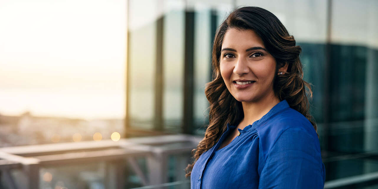 A businesswoman on a balcony overlooking a city