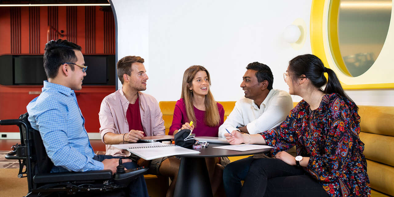 Students sitting at a table smiling and chatting