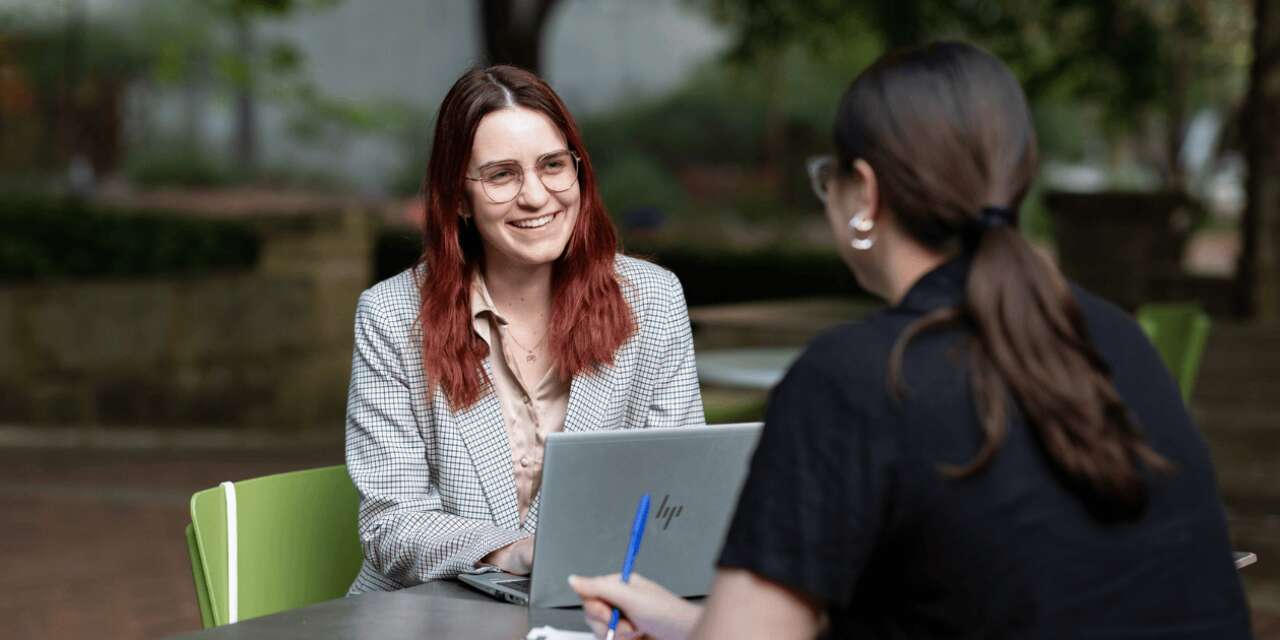 Student sitting at an outdoor table and smiling