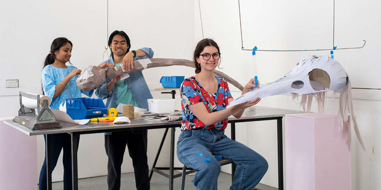 Three students working on different art projects.