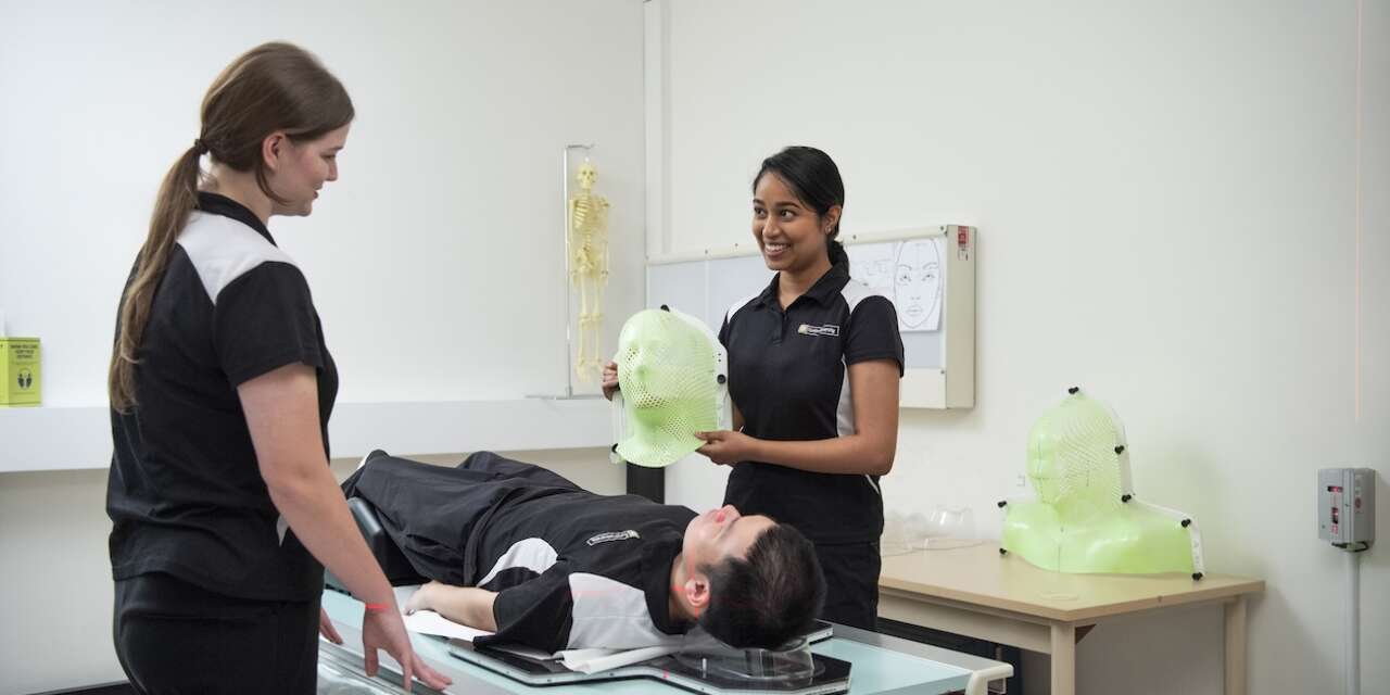 2 students standing beside a student laying down