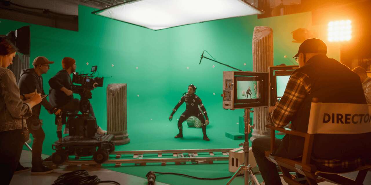 A film crew filming in front of a green screen.