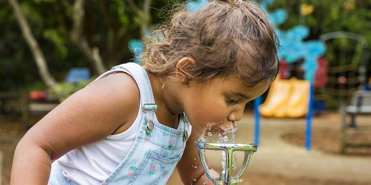 Young girl drinking from a water fountain