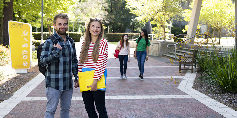A male and female student standing on a footpath, talking
