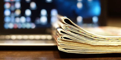 Newspaper placed in front of a laptop