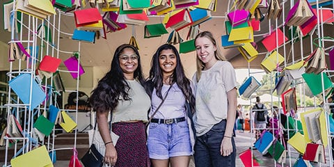 A group of girls, standing next to a pile of books