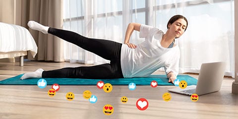 A young woman does yoga live. Side view. There's a laptop on the floor.