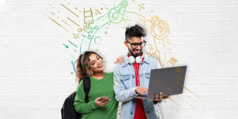Two young students looking at a laptop and smiling
